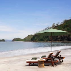 Relax by the ocean with a serene view of the lush hillside, a perfect spot for unwinding.