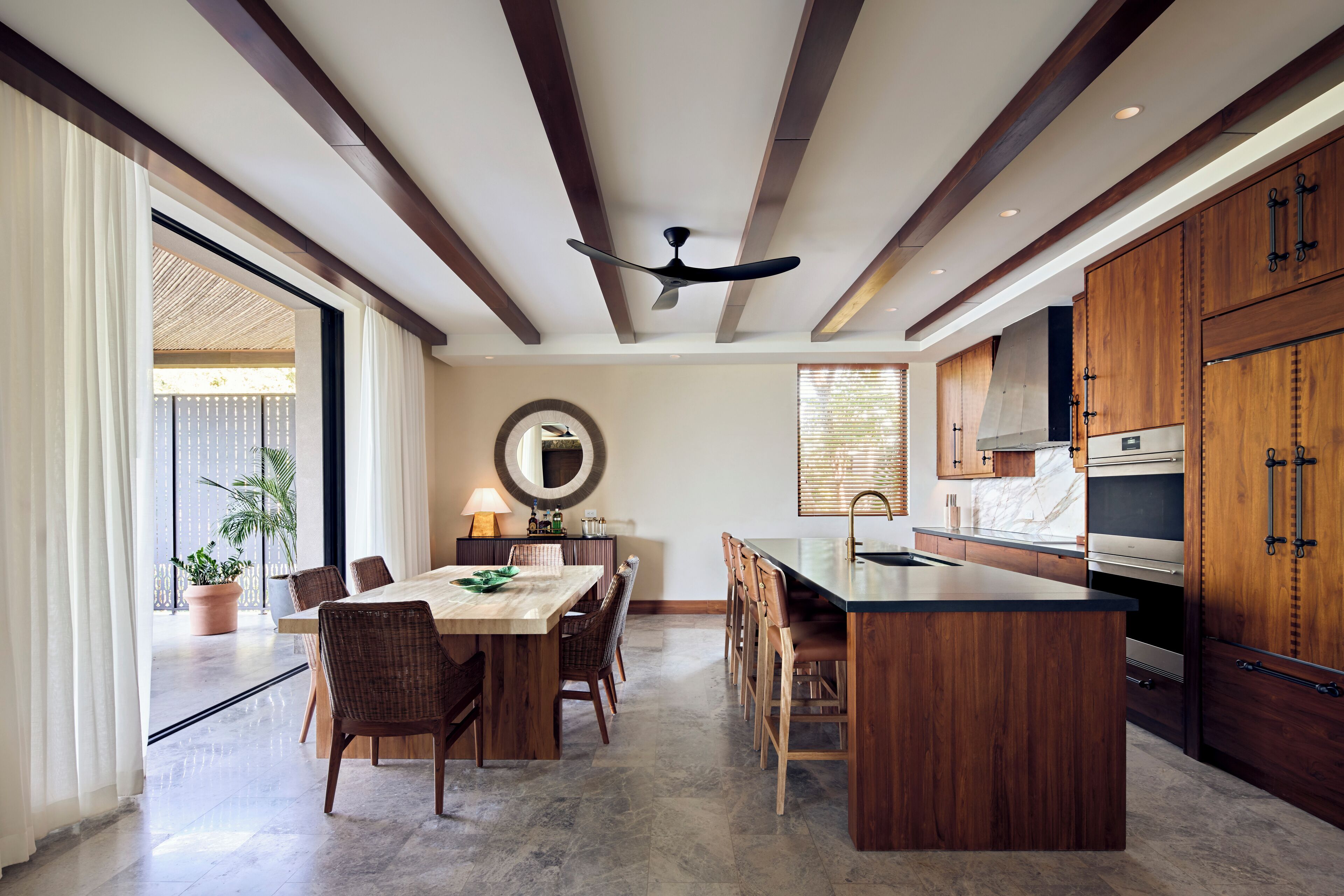 Une cuisine moderne avec des meubles en bois, un îlot central et un coin repas comprenant une table et des chaises.