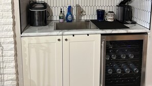 A compact kitchen with white cabinets, a built-in oven, a sink, and a wine rack.