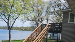 A wooden staircase leading to a deck, a small shed, and a lake view.