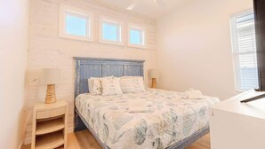 A bedroom with a bed, a nightstand, a ceiling fan, and a window. - Private Pool & Rooftop Deck w/ Water Views (Port Aransas)