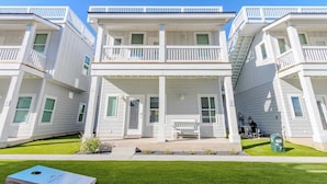 A row of white beachfront condominiums with balconies, a covered front porch, and a grassy lawn. - Private Pool & Rooftop Deck w/ Water Views (Port Aransas)