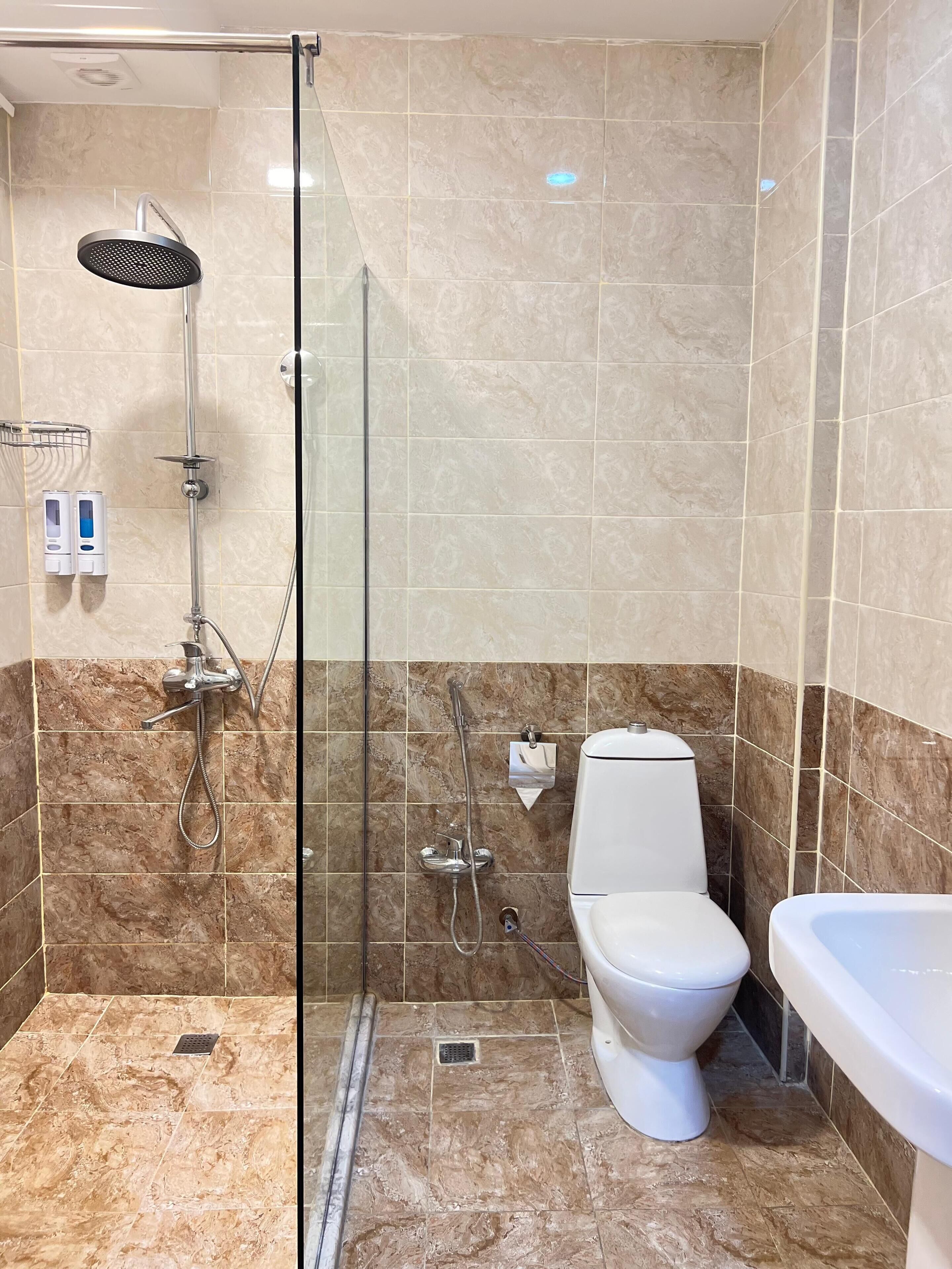 A bathroom with a glass-enclosed shower, a toilet, and a sink.