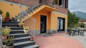 Ein Gebäude mit gelber Fassade, einer Treppe mit Blumentöpfen und einer Terrasse mit Sitzgelegenheiten.