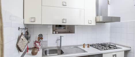A modern kitchen with white cabinets, a stainless steel sink, and a gas stove.