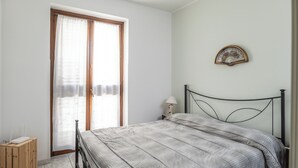 A bedroom with a bed, a wooden nightstand, a lamp, and a wall-mounted decorative item. - Casa Del Sarto (Sperlinga)
