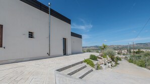 A modern building with a flat roof, a paved entrance with steps, and a clear view of the surrounding landscape. - Villa Ginevra (Santa Ninfa)