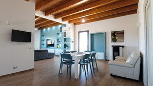 A spacious living area with a wooden ceiling, a dining table with chairs, a sofa, and a fireplace. - Villa Ginevra (Santa Ninfa)