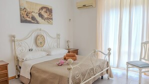 A bedroom with a bed, a nightstand, a chair, a painting, and an air conditioning unit. - Casa Vacanza Mary (Guardavalle)