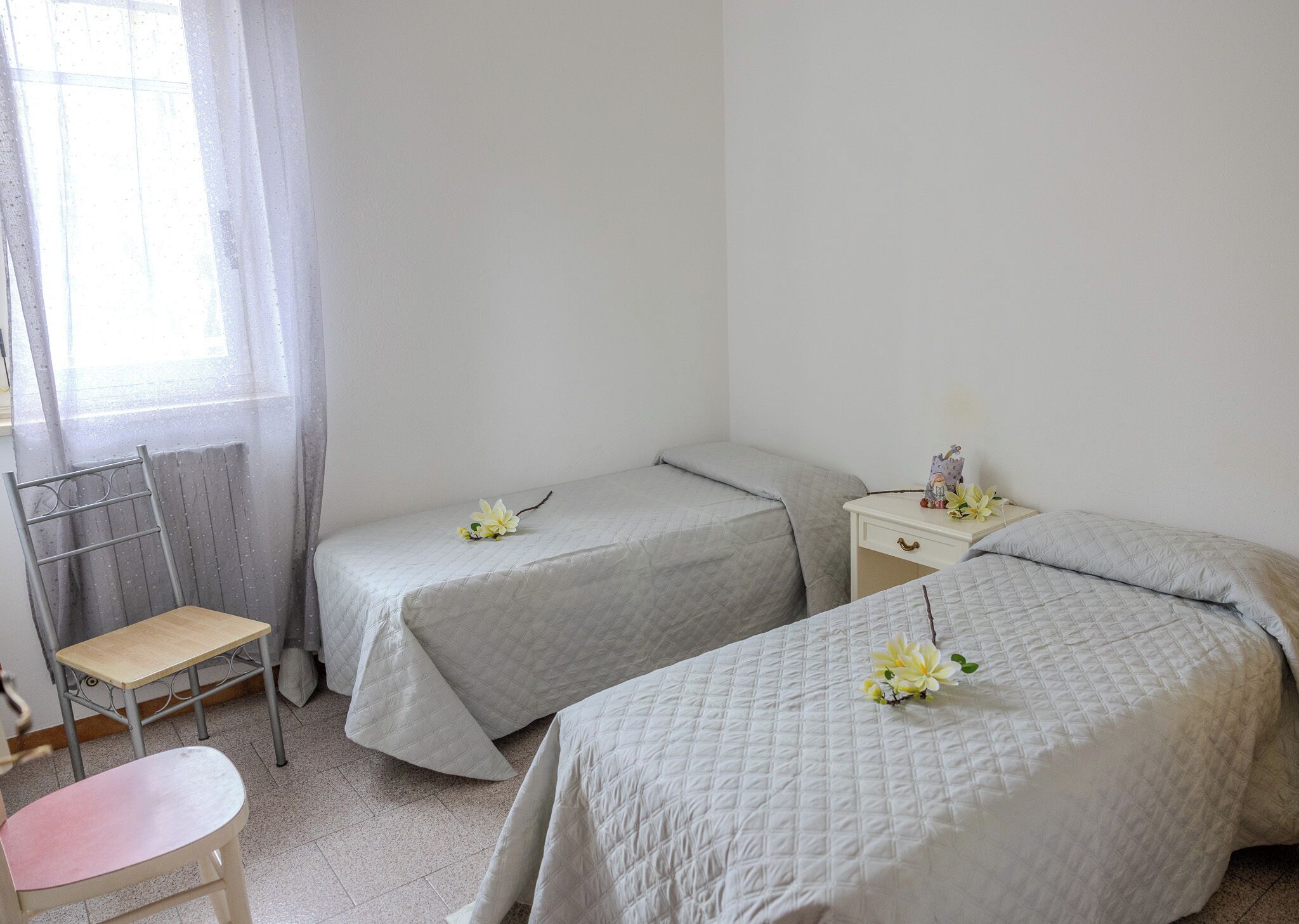 Una habitación sencilla y limpia, con dos camas, una silla y una mesita.