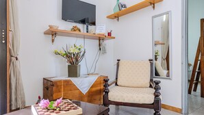A cozy living room with a wooden cabinet, a chair, a table with a chessboard, a television, and a mirror. - Casa Vacanza Mary (Guardavalle)