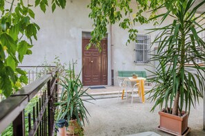 A courtyard with a wooden door, a bench, a table, and potted plants. - Casa Vacanza Mary (Guardavalle)