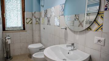 Un bagno con un lavandino bianco, un water e un bidet. Le pareti sono rivestite con diversi motivi.