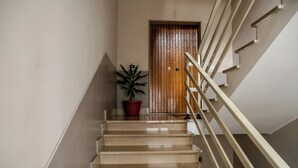 A staircase with a wooden door at the top, a potted plant, and a handrail.