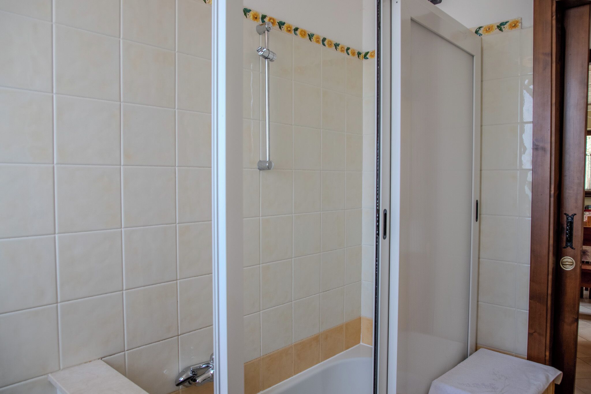 A bathroom with a glass-enclosed shower, a white sink, and a wooden door.