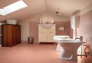 A bathroom with a skylight, a sink, a toilet, and a cabinet. - A Casa Di Lea (Mondavio)
