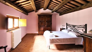 Un dormitorio con techo de madera, cama, mesita de noche, armario y ventana con lámpara.