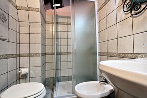 Ein Badezimmer mit Toilette, einer Duschkabine und einem Waschbecken.