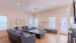 A spacious living room with a gray sectional sofa, a coffee table, and a TV on a stand. - Driftwood Delight *private Pool!*Beachway Bungalow (Port Aransas)
