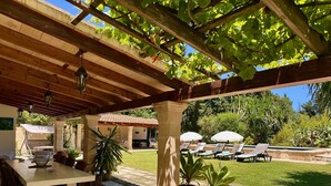 Une terrasse extérieure dotée d’une pergola, d’une table avec des chaises et d’un espace piscine avec des chaises longues.