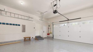 Ett rymligt inomhusområde med ett polerat golv, en träbänk, en trappa och en garageport.