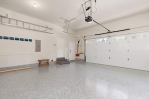 Un vaste espace intérieur doté d’un plancher poli, d’un banc en bois, d’un escalier et d’une porte de garage.