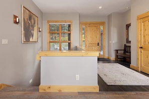 A hallway with a wooden bench, a large window, and a door.