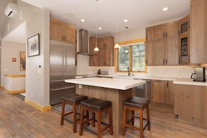 A modern kitchen with wooden cabinets, stainless steel appliances, and a central island with stools.