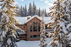 A cabin with a wooden exterior, large windows, and a balcony. - Lovely renovated home w/ hot tub & stunning views (Big Sky)