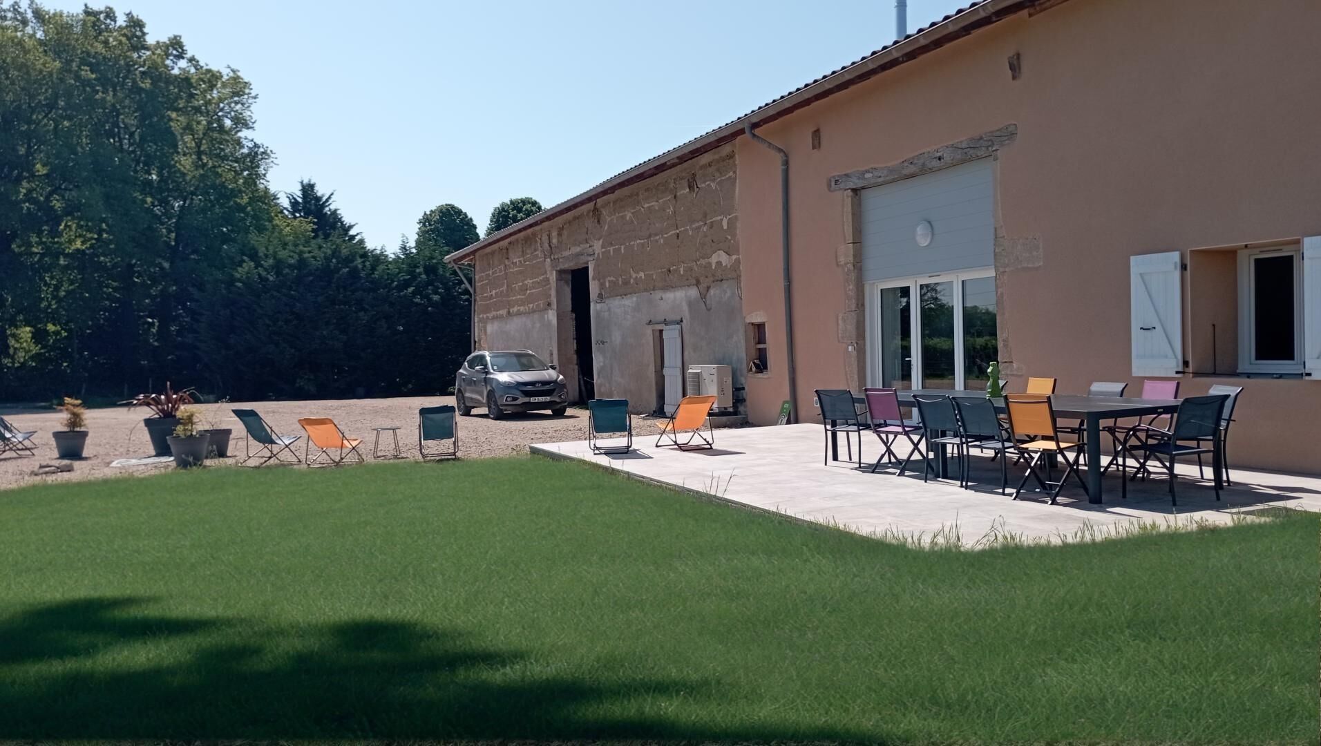 Edificio con patio que tiene mobiliario exterior y un coche estacionado al frente.
