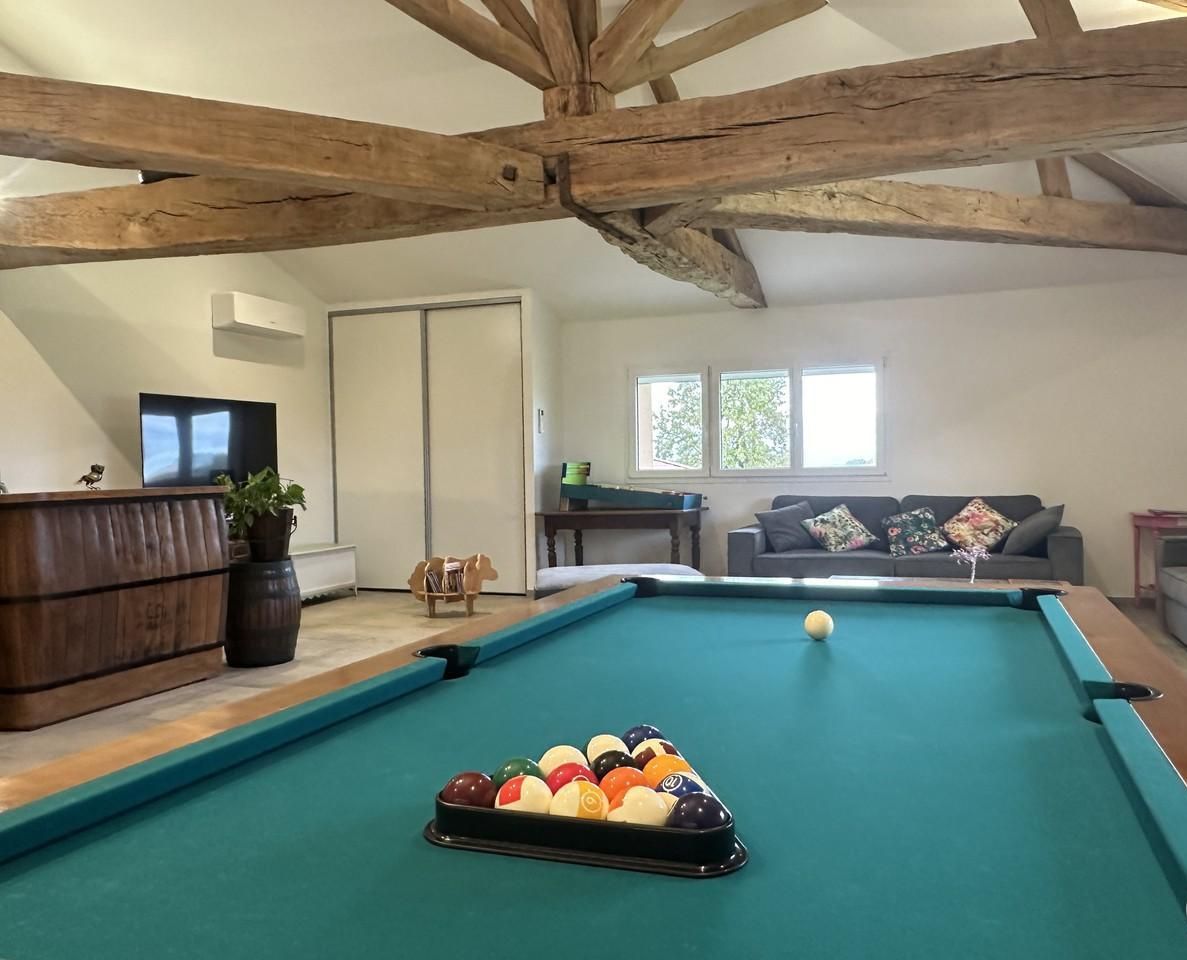 A pool table with balls, a sofa, and a wooden ceiling.