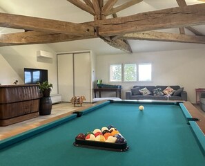 A pool table with balls, a sofa, and a wooden ceiling.