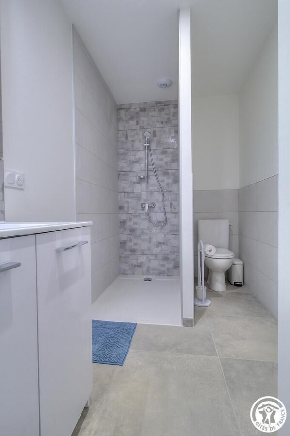 A modern bathroom with a shower, toilet, and sink.
