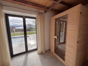 Ein Zimmer mit einer Schiebeglasdoor zum Patio, einer Holzsauna und einem gefliesten Boden.