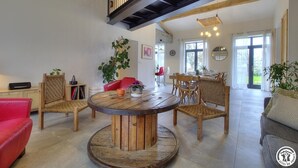 Un salon spacieux avec une table ronde en bois, des chaises en osier et un canapé rouge.