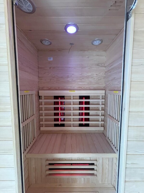 A sauna with a wooden interior, a bench, and a ceiling with three lights.