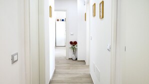 Un pasillo con paredes blancas, suelo de madera y una puerta al final.