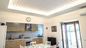 Una cocina con armarios de madera, una estufa a gas, un reloj y una mesa de comedor con sillas.