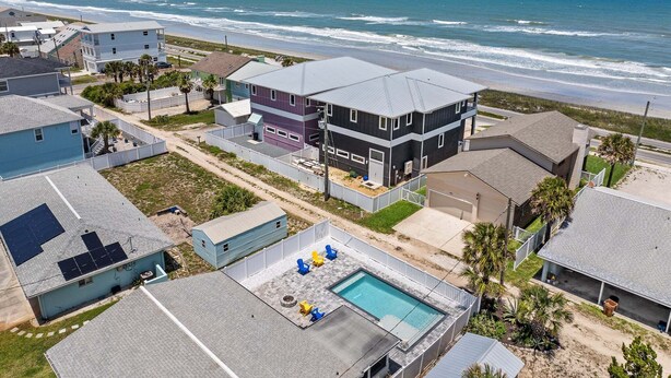 A coastal residential area with houses, a swimming pool, and a view of the ocean.