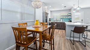 A modern kitchen with a central island, wooden dining table, and chairs.