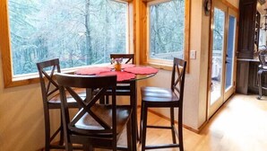A dining area with a table and chairs, large windows, and a wooden ceiling. - The Mountain House- ultra quiet, secluded (Corvallis)