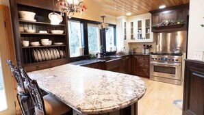 A kitchen with a central island, wooden cabinets, stainless steel appliances, and a chandelier. - The Mountain House- ultra quiet, secluded (Corvallis)
