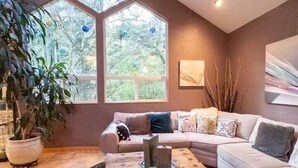 A modern living room with a large window, a wooden coffee table, and a sofa. - The Mountain House- ultra quiet, secluded (Corvallis)
