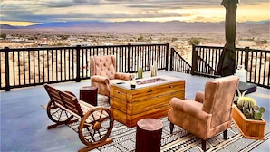 A balcony with a wooden table, two chairs, a wooden chest, and a potted cactus. - Magical Vibes on 5 Acres with panoramic views. (Joshua Tree)