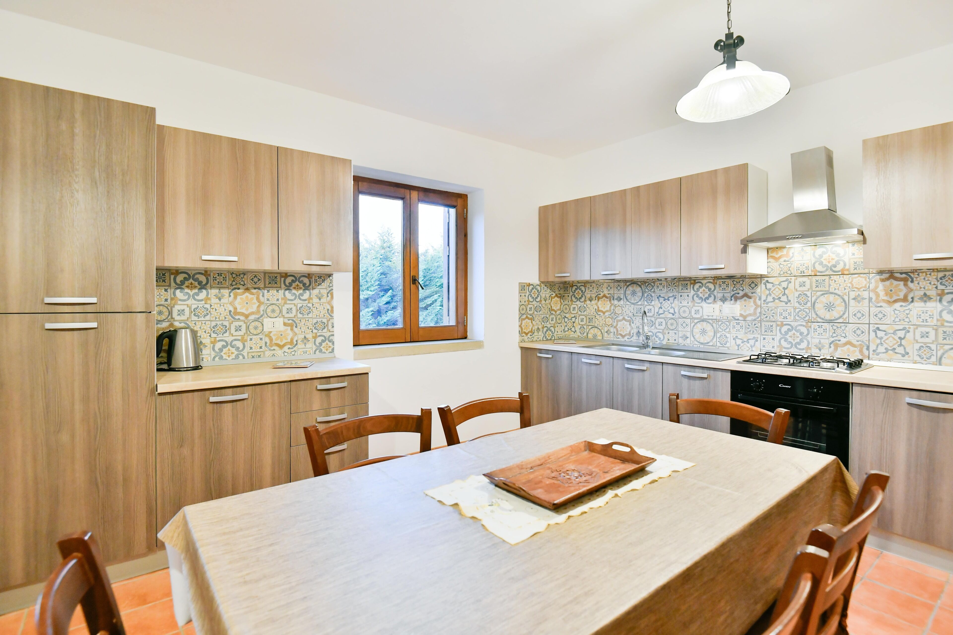 A modern kitchen with wooden cabinets, a tiled backsplash, and a dining table with chairs.