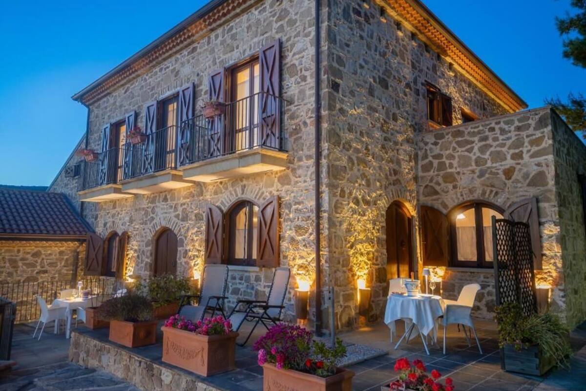 A stone building with outdoor seating and a balcony.