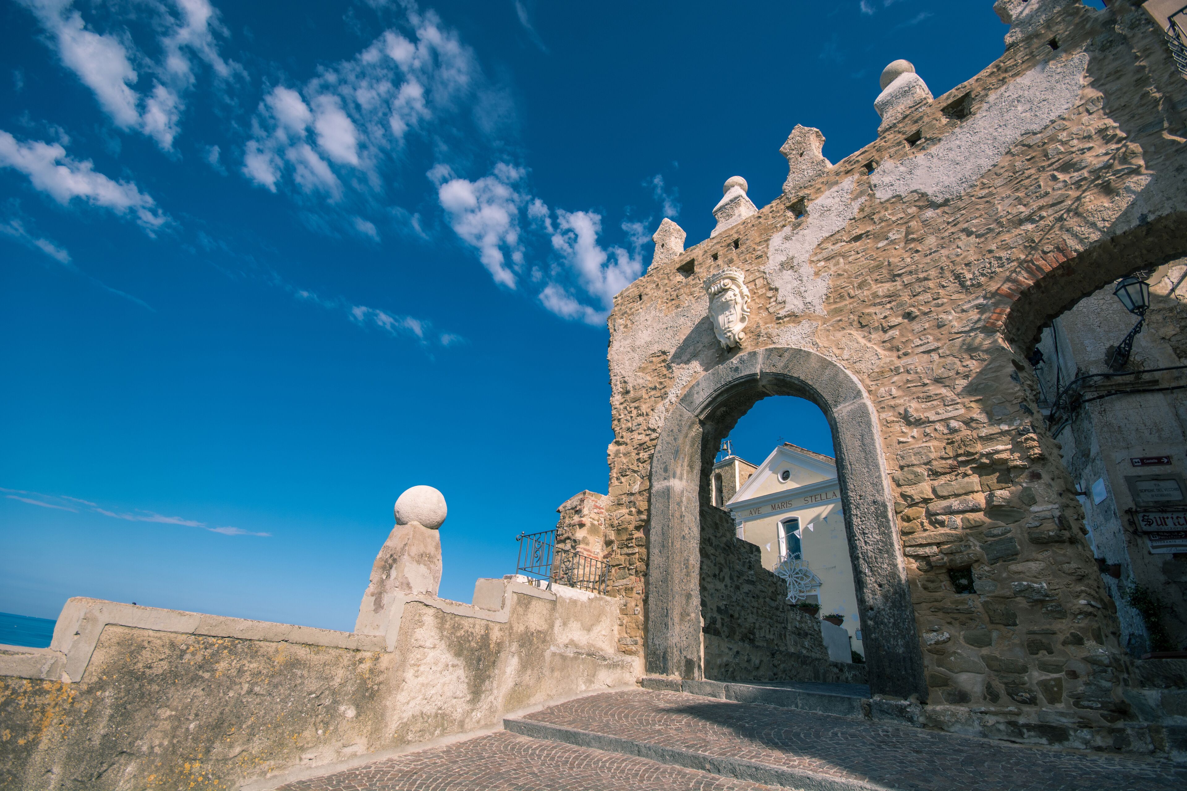 Un antiguo arco de piedra que conduce a un edificio con una cúpula y un cartel que dice 'Villa Maria Stella'.