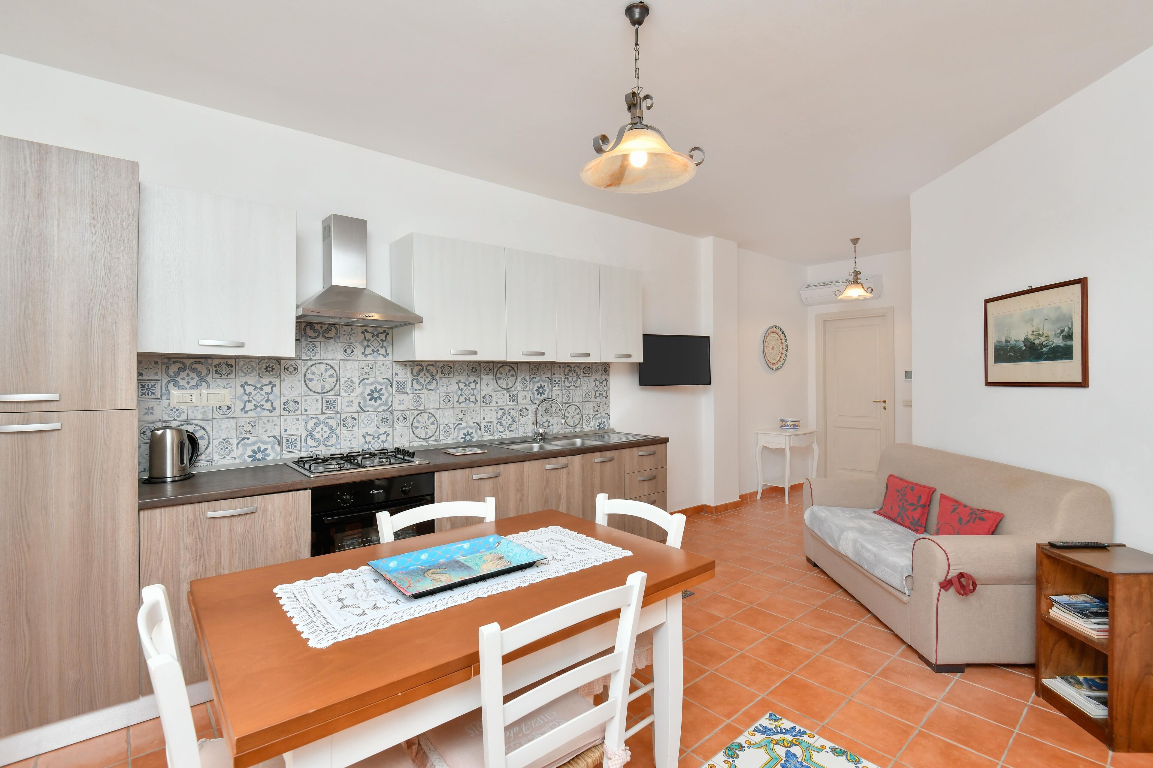 A compact kitchen with white cabinets, a tiled backsplash, and a dining table with chairs.