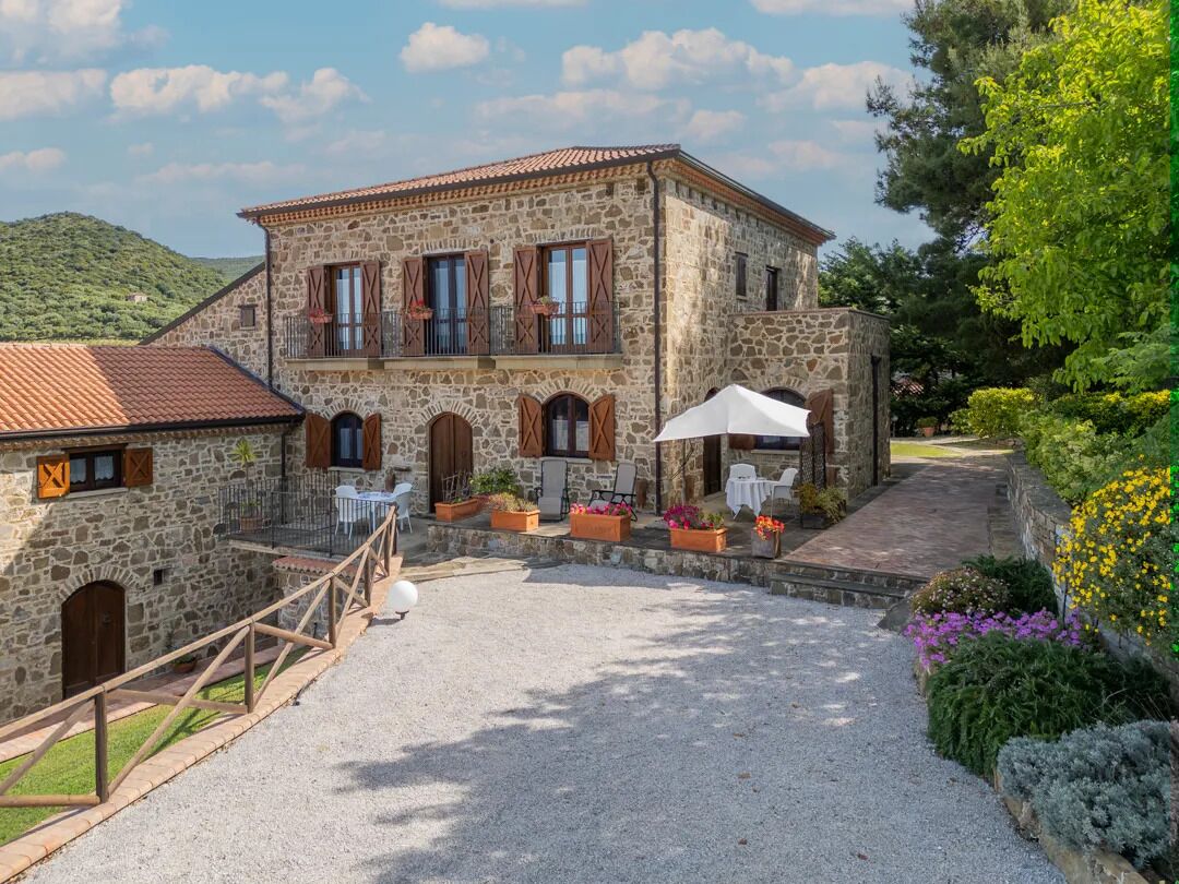 A stone building with a courtyard, outdoor seating, and a gravel path.