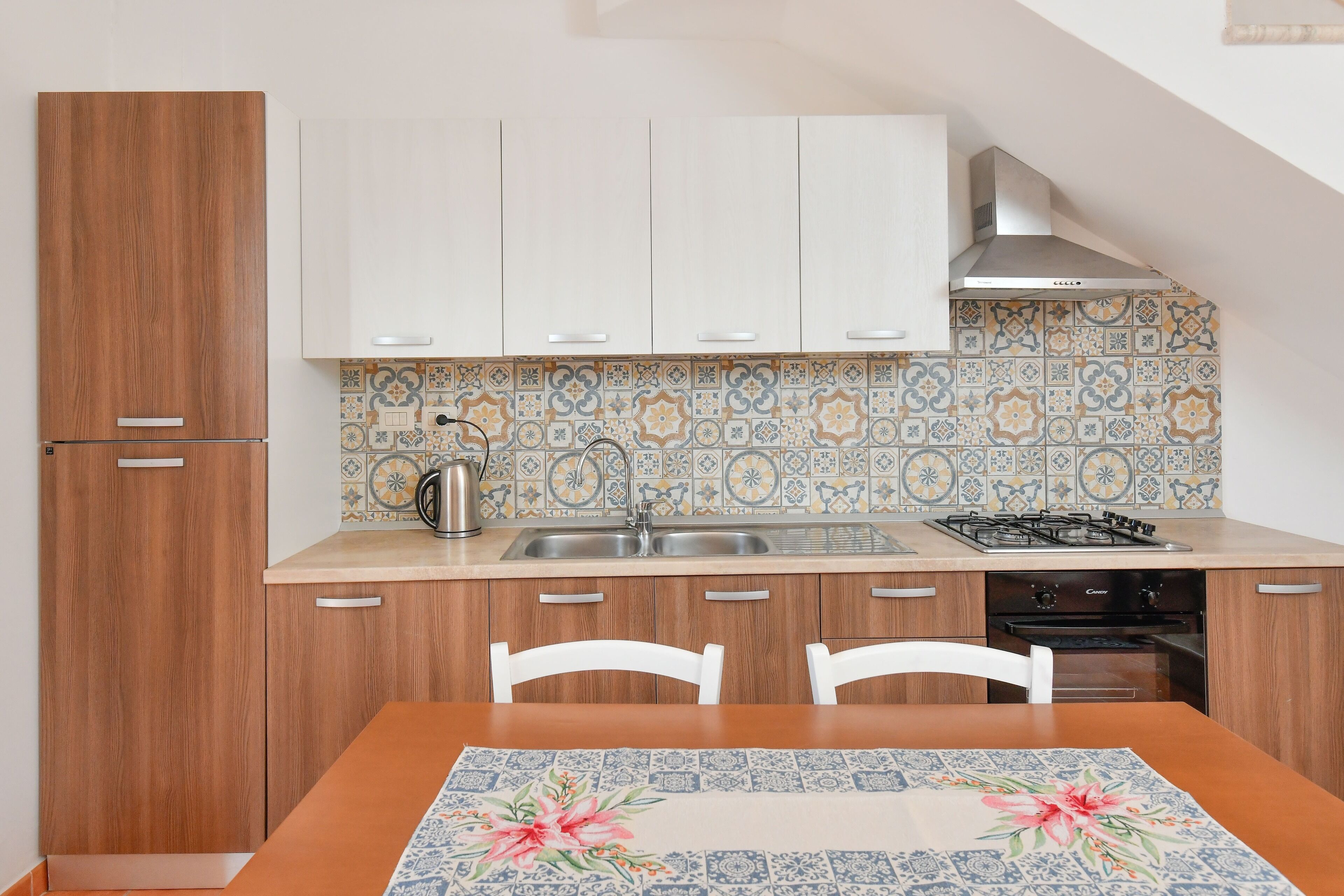 A kitchen with wooden cabinets, a tiled backsplash, a gas stove, and a sink.